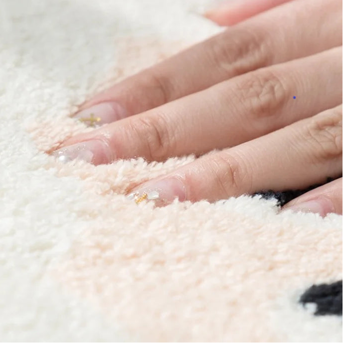 Close-up of a hand touching a soft, white kawaii rug
