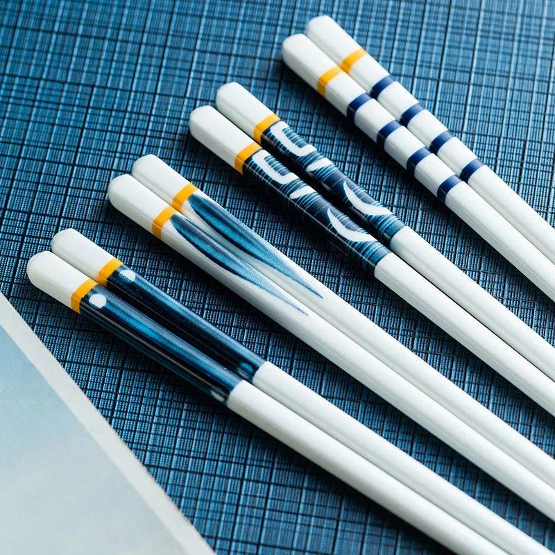 Set of white kawaii chopsticks with blue and yellow patterns on a blue checkered background