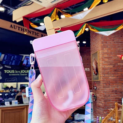 Pink ice cream-shaped kawaii water bottle held in front of a store interior.