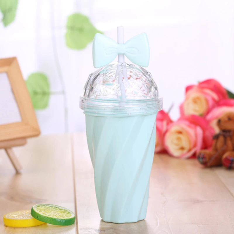 Light blue kawaii tumbler with a clear lid on a wooden surface with flowers and a frame in the background