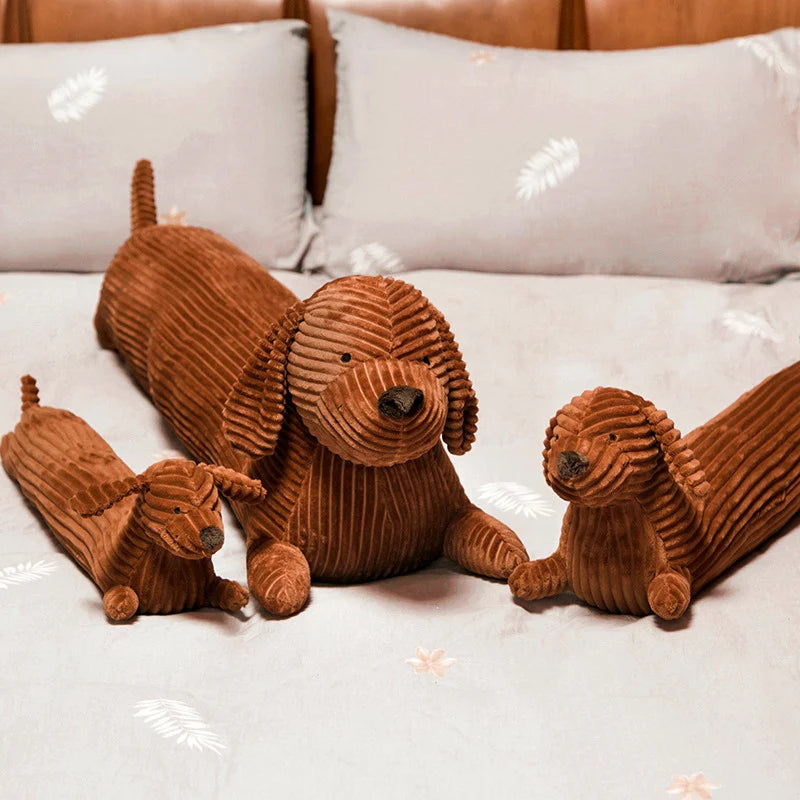 Three brown corduroy dog toys on a bed with white kawaii pillows.