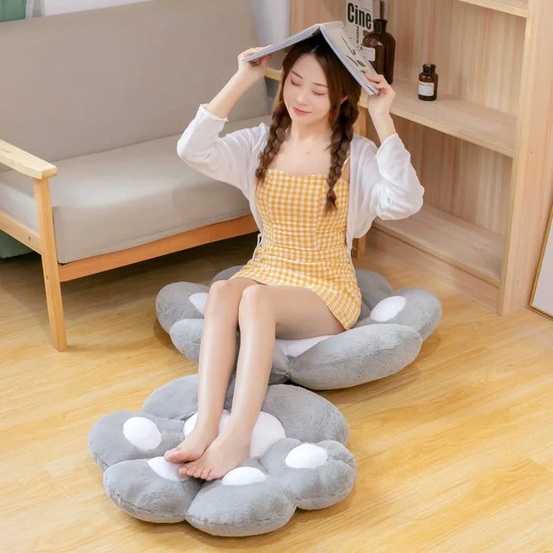 Woman sitting on a cloud-shaped kawaii cushion in a room with a sofa and bookshelf.