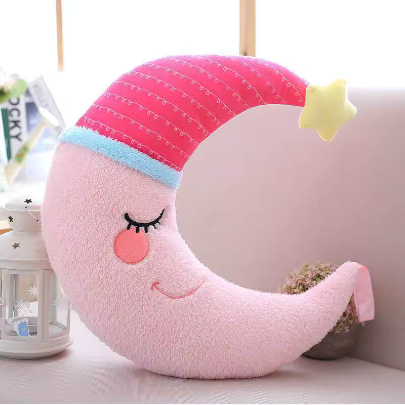 Pink crescent moon kawaii plush toy with a face on a white surface