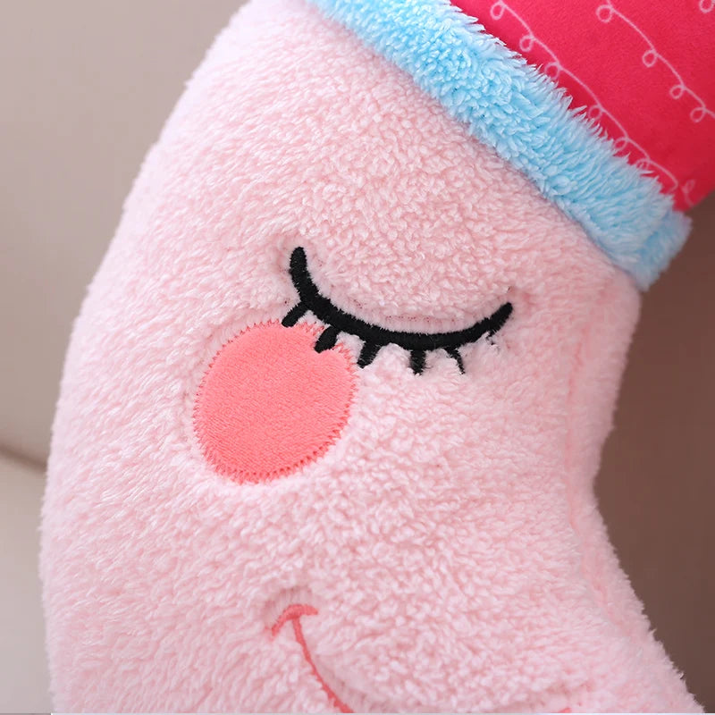 Close-up of a pink kawaii plush toy with closed eyes and a red hat.