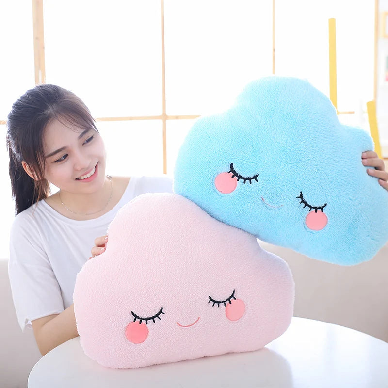 Person holding two cloud-shaped kawaii plush toys with facial expressions against a neutral background
