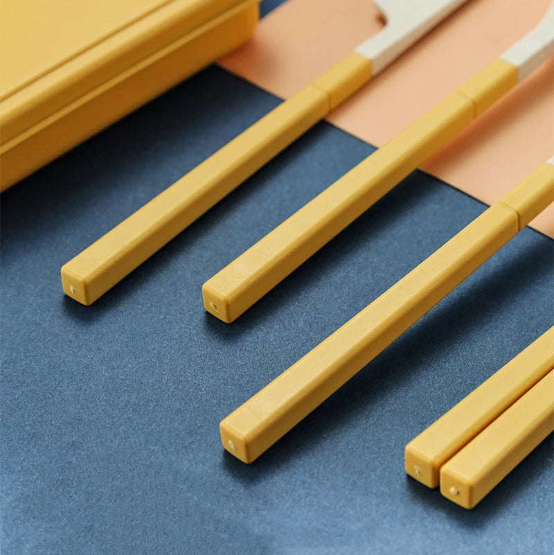 Set of yellow kawaii utensils with a case on a blue surface