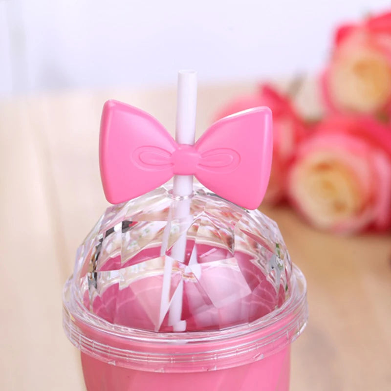 Pink kawaii tumbler with a bow design and straw on a blurred floral background
