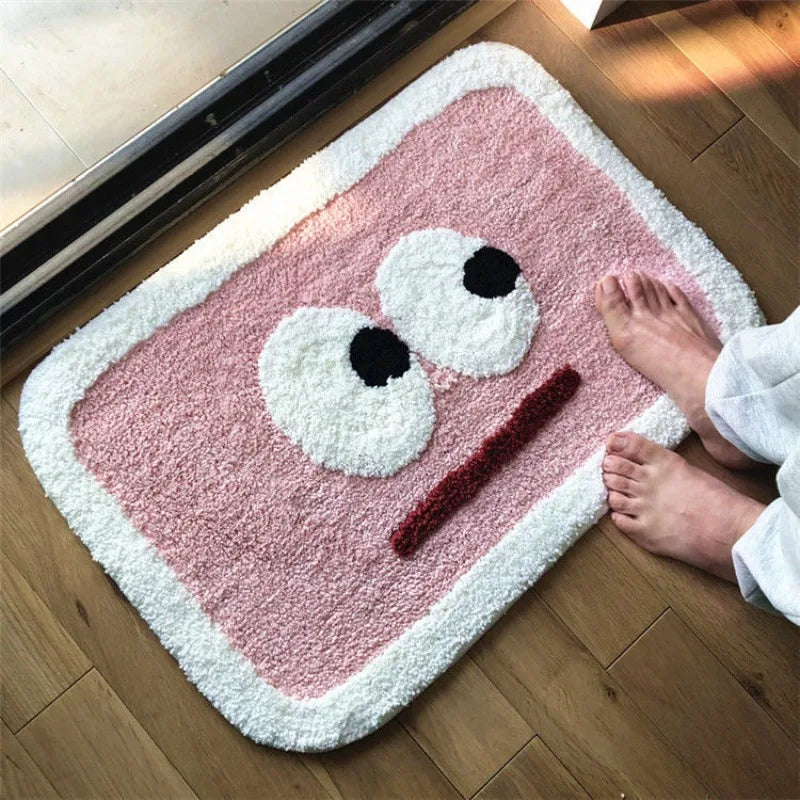 Pink Kawaii-style rug with a face design on a wooden floor.