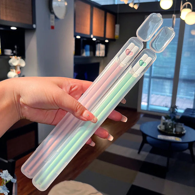 Hand holding a set of kawaii chopsticks with colorful ends in a kitchen setting.