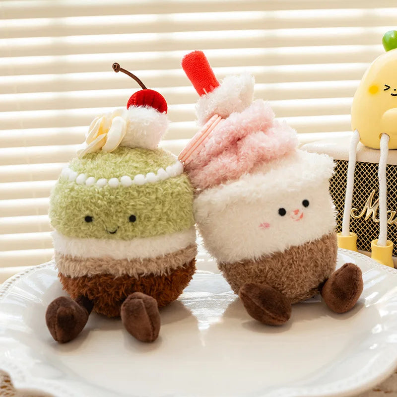 Two kawaii plush toys resembling cake slices with cherry and whipped cream on a white surface.