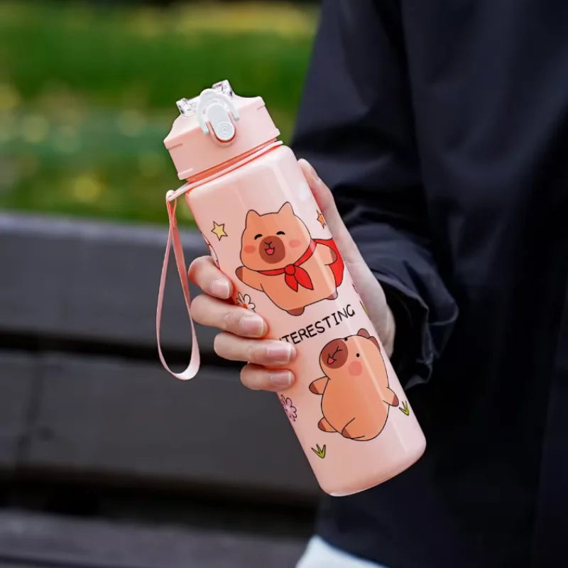 Person holding a pink kawaii water bottle with cartoon designs outdoors