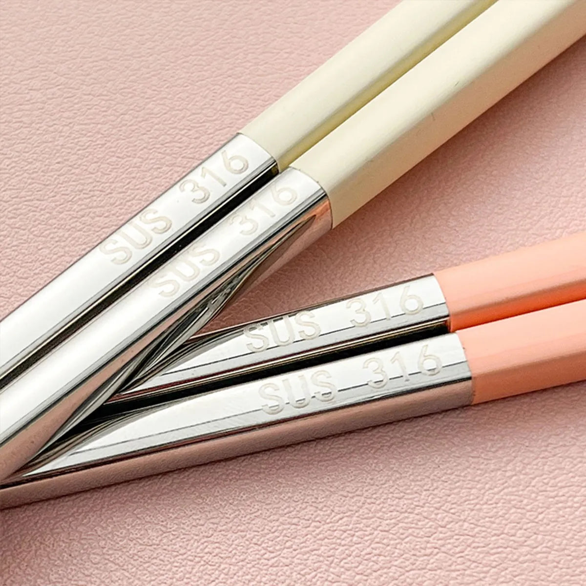 Three kawaii chopsticks with silver ferrules and pink handles on a pink background