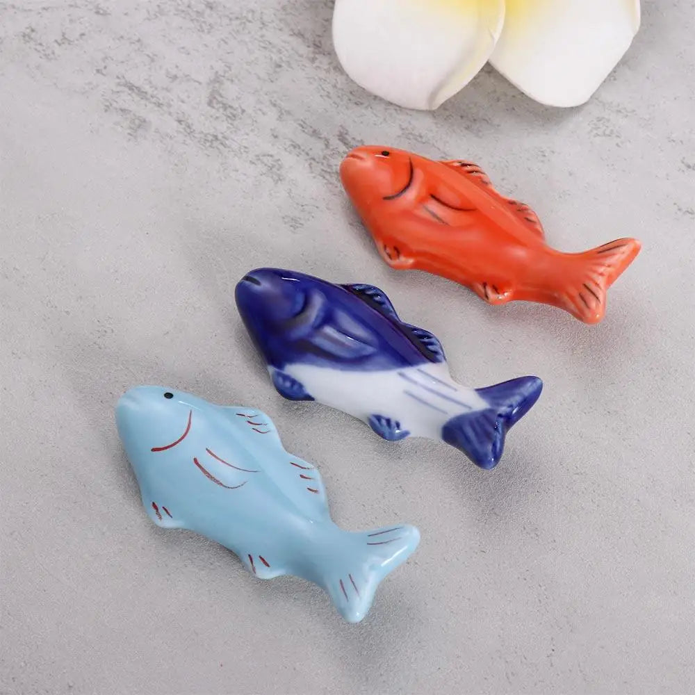 Three fish shaped kawaii chopsticks holders sitting on a tabel