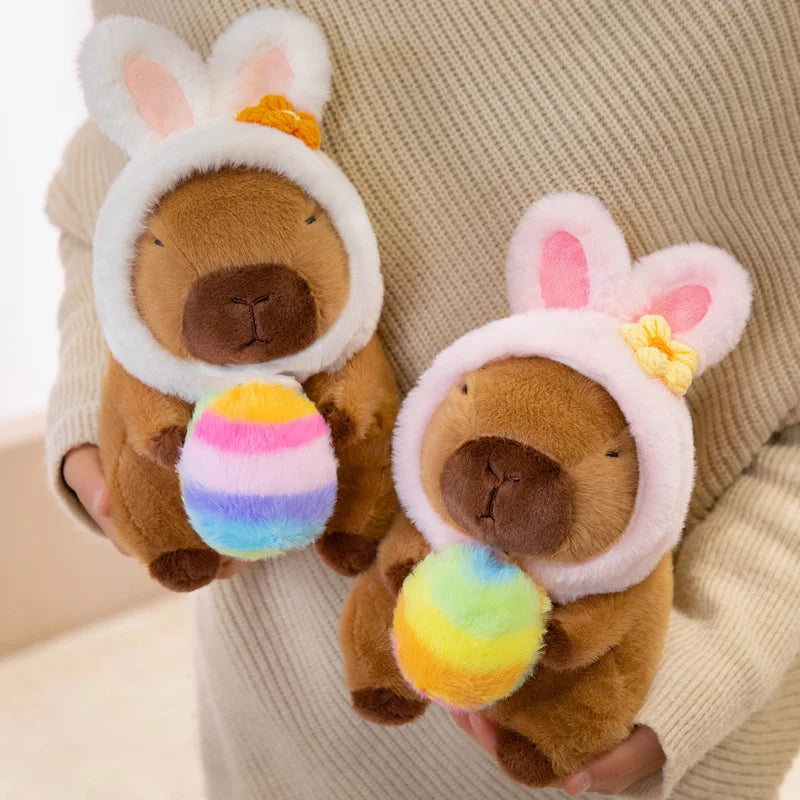 Pair of brown bear kawaii plush toys with bunny ears and colorful eggs held by a person wearing a beige sweater.