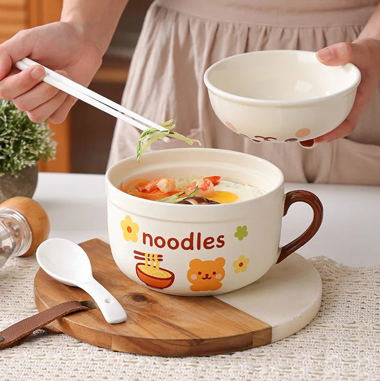 Person holding a kawaii ramen bowl with a lid, which can be used as a regular bowl or a rice bowl, on a wooden cutting board.