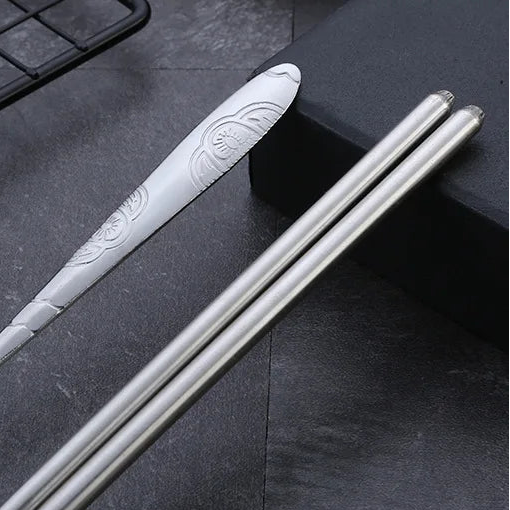 Silver kawaii utensils with decorative handle on a dark surface