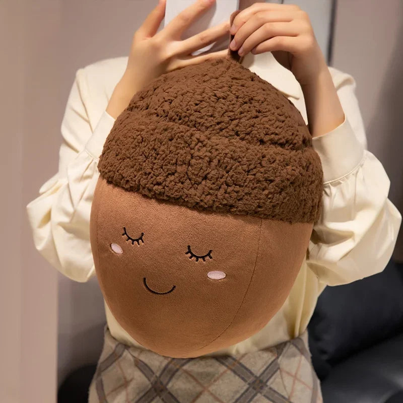 Person holding a kawaii plush toy shaped like an acorn with a face design.