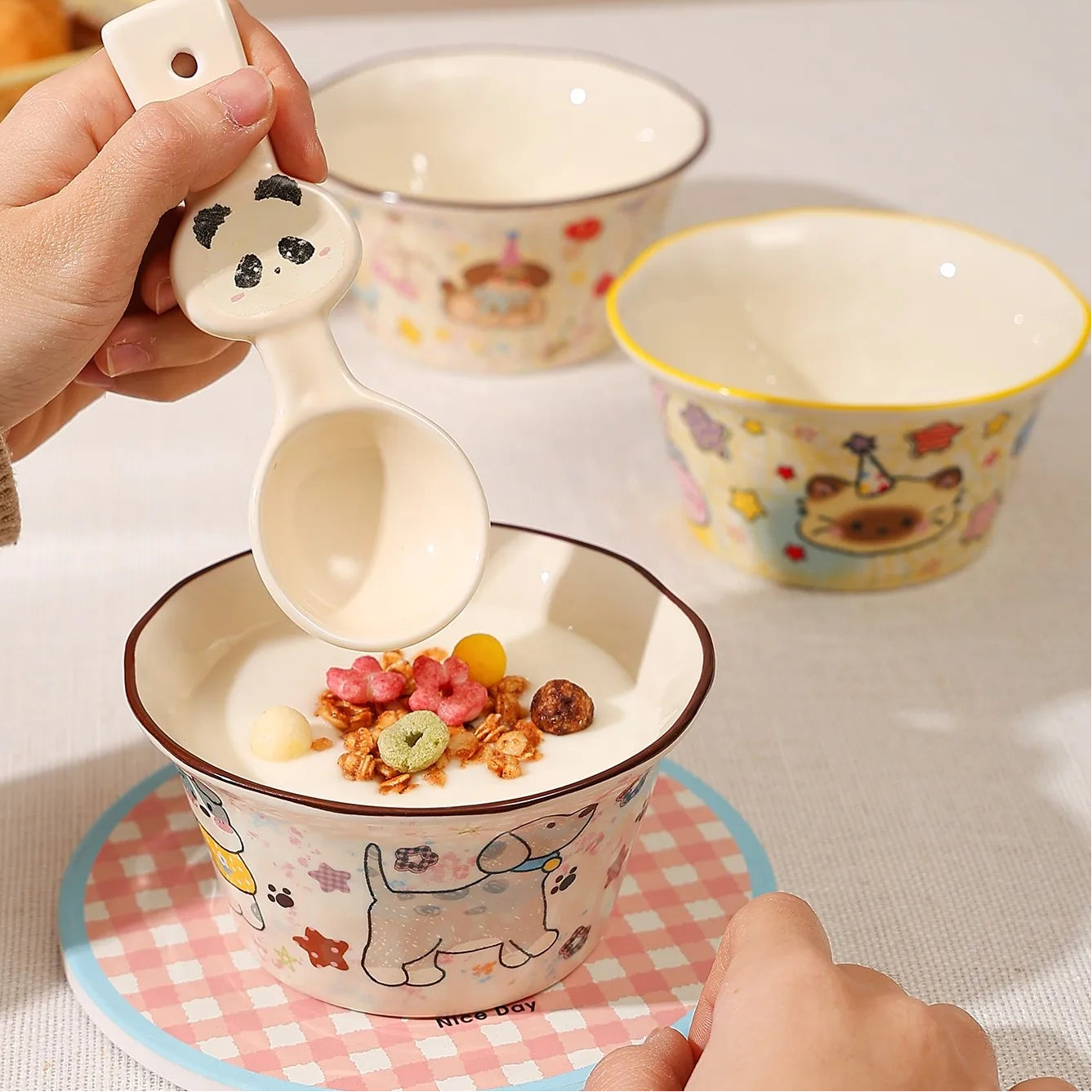 Ceramic kawaii ramen bowls with cute designs on a table, featuring text about underglaze color and baked flower design.