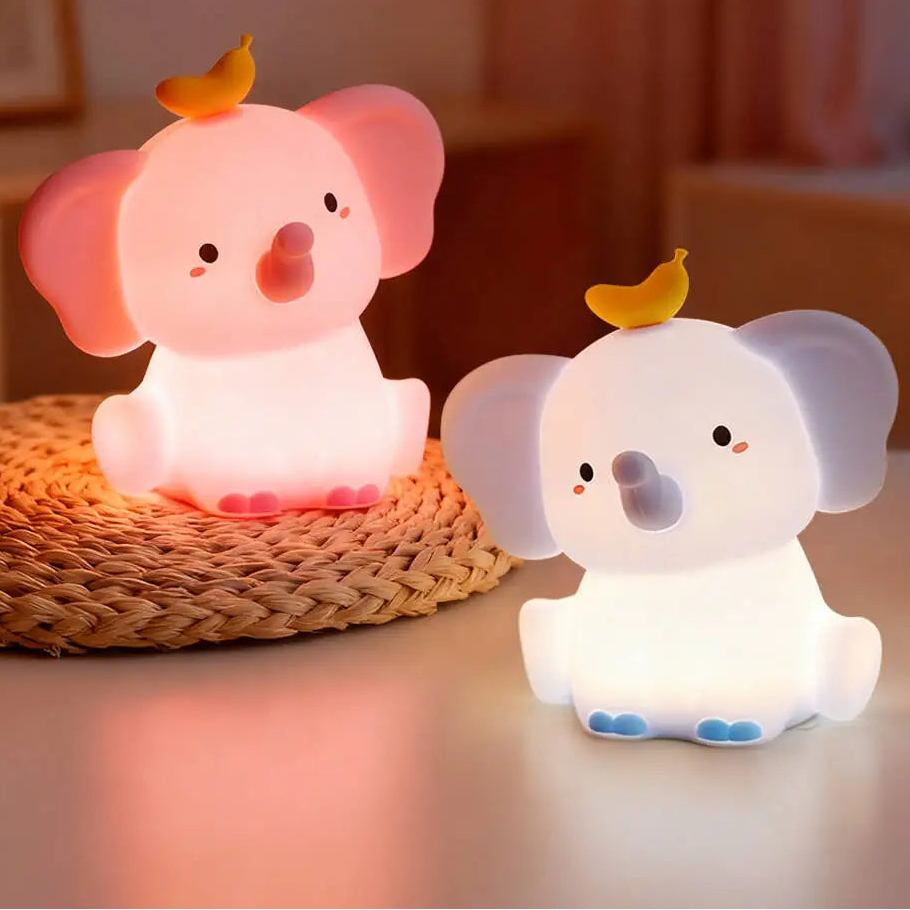 Two cartoon elephant kawaii night lights on a surface with a blurred background