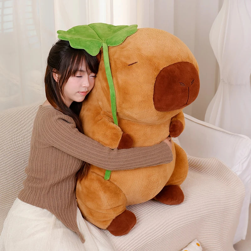 Person hugging a large kawaii plush toy resembling a brown creature with a green leaf on its head.