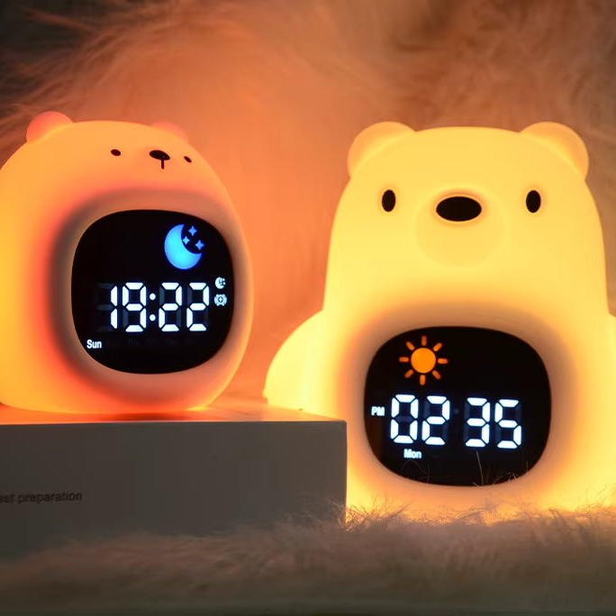 Two bear-shaped digital alarm clocks on a soft white faux-fur surface, one lit in warm peach-orange and the other in bright yellow, both showing illuminated screens with moon and sun icons.