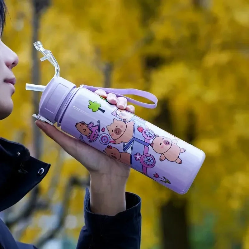 Person holding a purple kawaii water bottle with cartoon designs against a blurred natural background