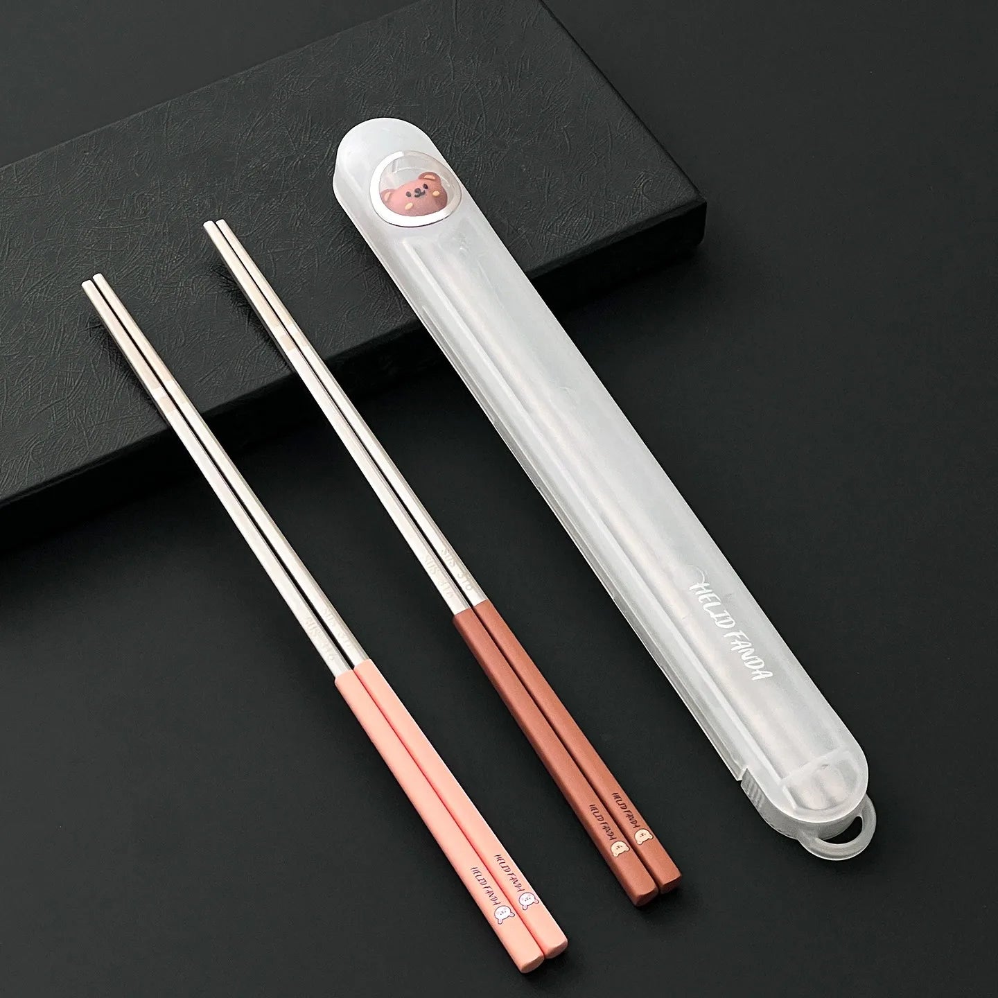 Pair of rose gold kawaii chopsticks with a clear case on a black background