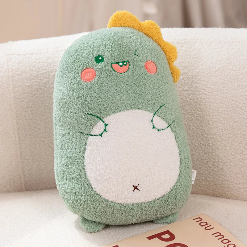 Kawaii plush toy resembling a green dinosaur with a yellow tuft of hair on a beige couch.