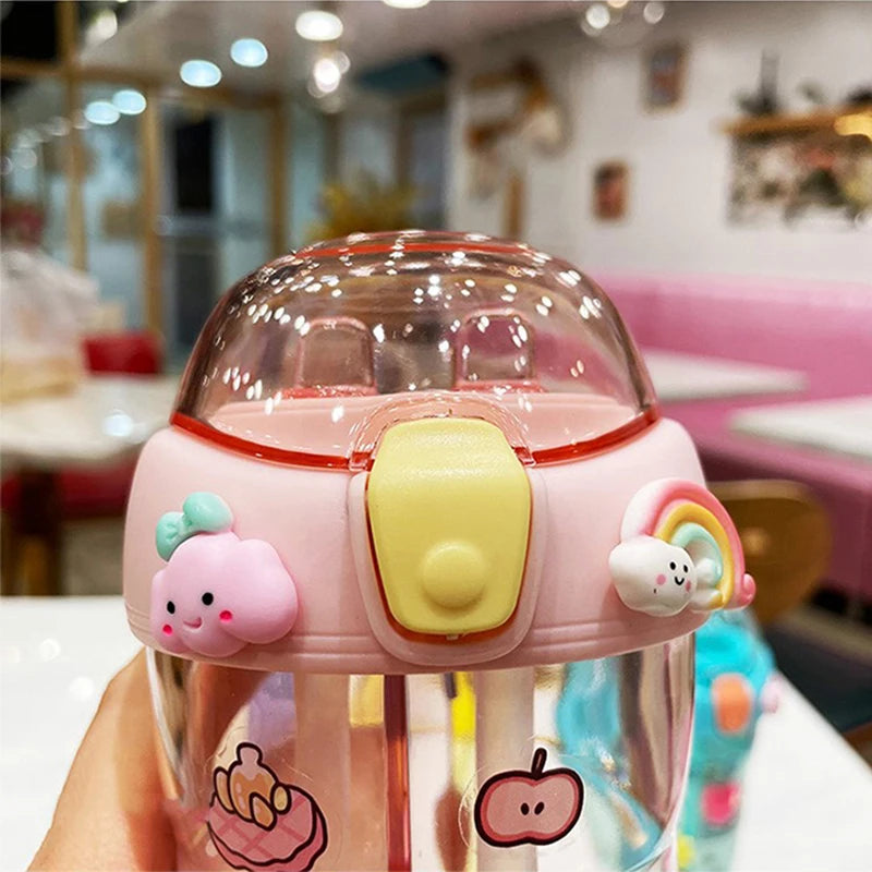 Pink cartoon-themed kawaii tumbler held in a hand with a blurred indoor background