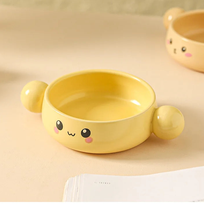Yellow ceramic kawaii ramen bowl with cartoon face design on a beige background