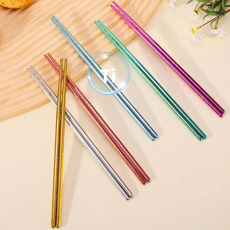 Set of colorful kawaii chopsticks on a light wooden surface with a glass of water.