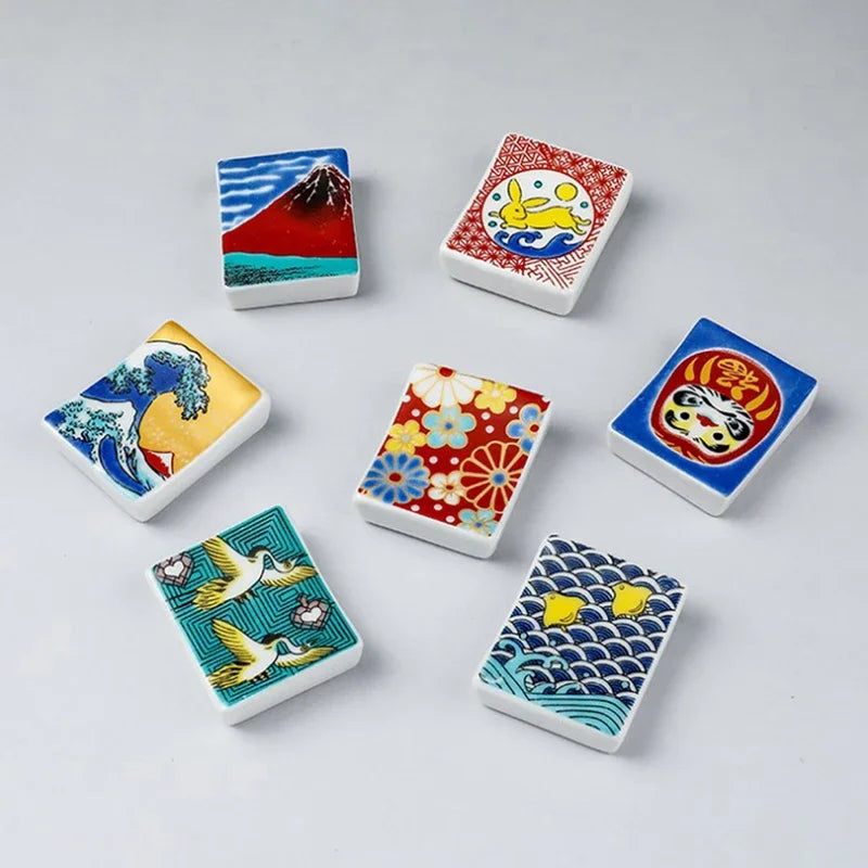 Set of colorful ceramic kawaii chopstick holders with various designs on a light gray background