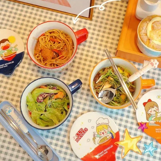 Table setting with kawaii ramen bowls including noodles and salad on a checkered tablecloth.