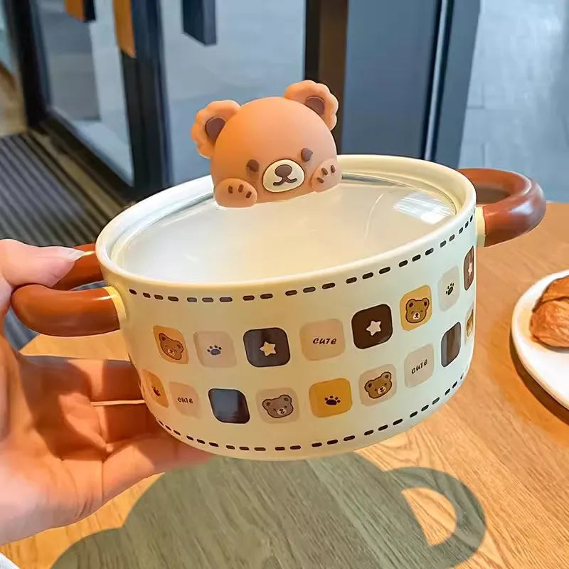Ceramic kawaii ramen bowls with bear design and lid, held by a hand on a wooden surface.