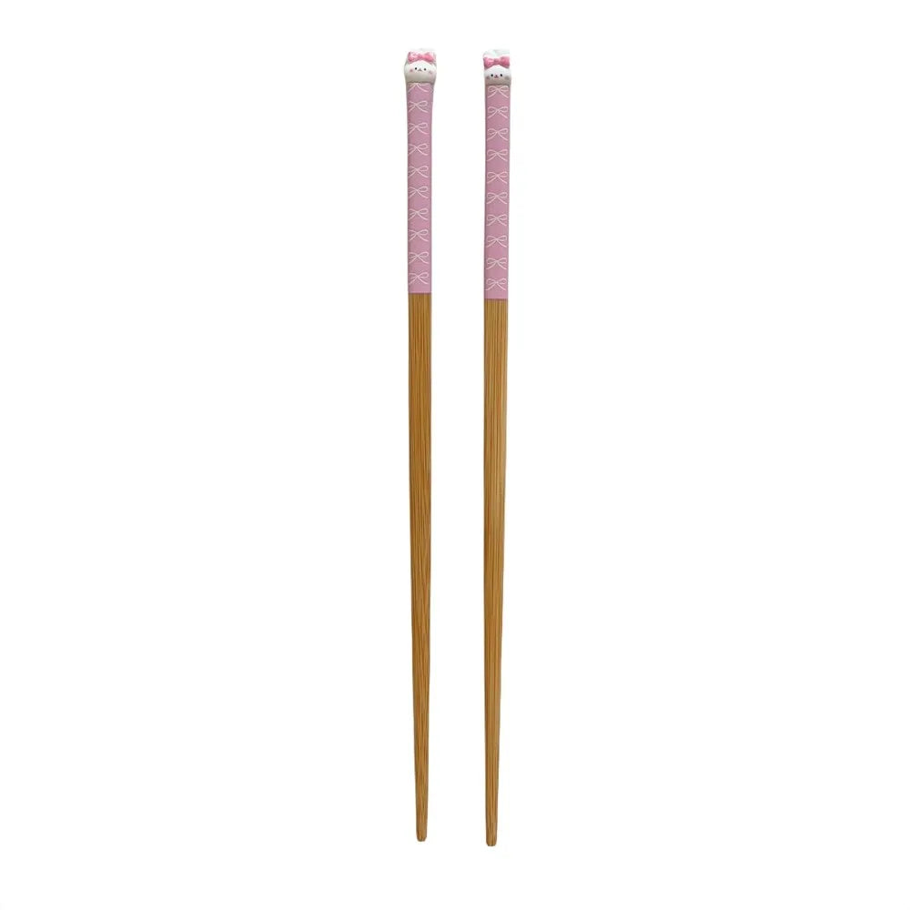 Pair of wooden kawaii chopsticks with pink ends on a white background