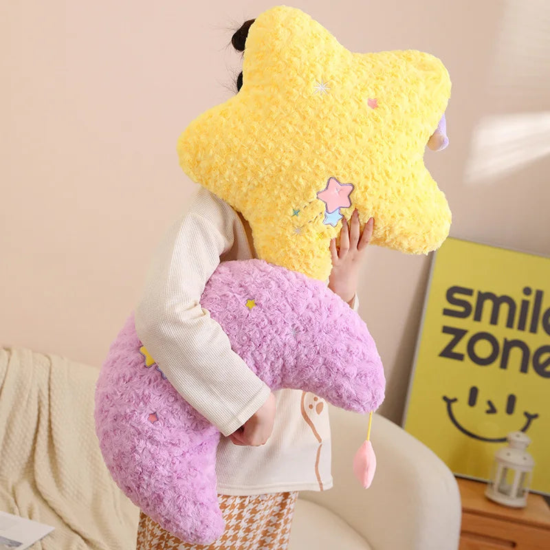 Person holding a yellow star-shaped kawaii pillow and pink heart-shaped pillow in a room with a 'smile zone' sign.