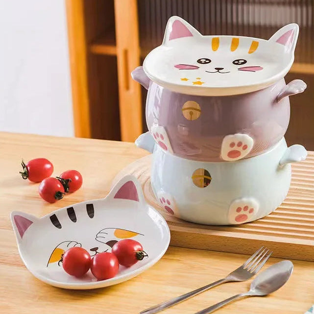 Cat-shaped ceramic kawaii ramen bowls on a wooden surface with tomatoes and cutlery.