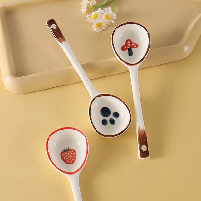 Three ceramic kawaii spoons with decorative ends on a yellow surface.
