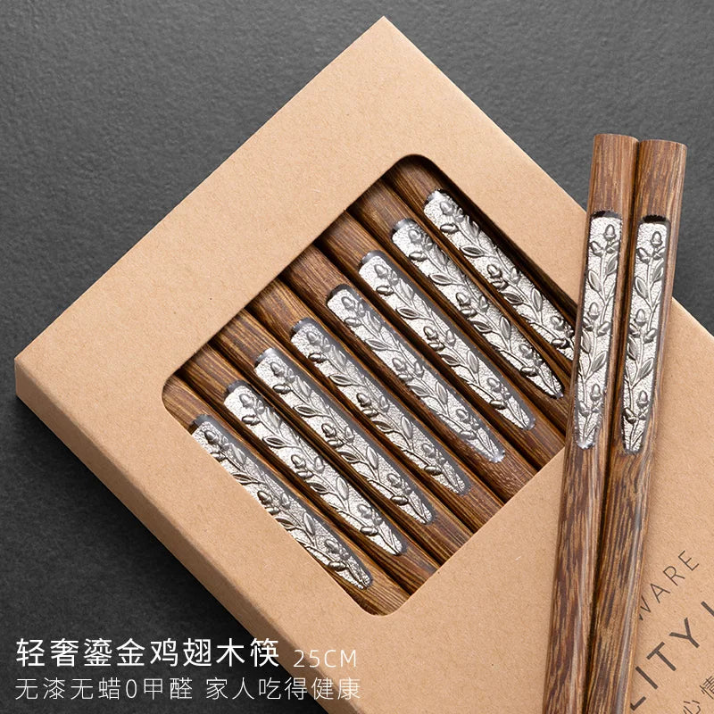 Set of wooden kawaii chopsticks with silver decorations in a brown box on a dark background