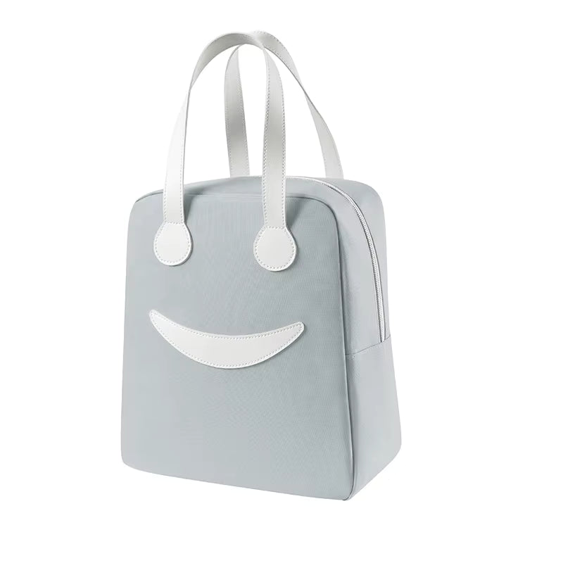 A light blue textured soft-sided bag with white handles and a white smiley face design on the front, shown against a plain white background.