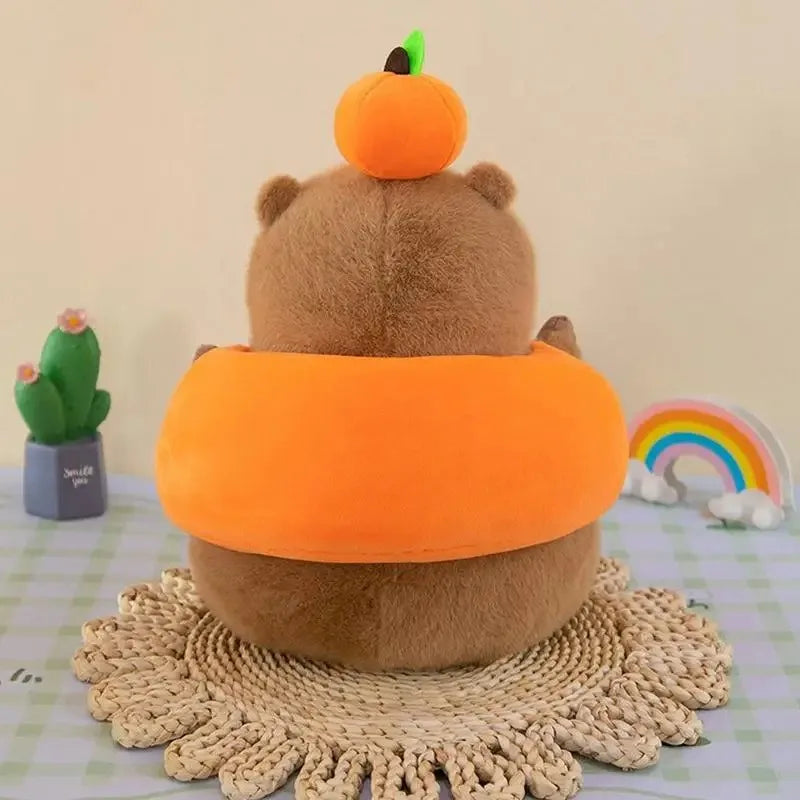 Kawaii plush toy shaped like a bear in an orange costume with a pumpkin on its head, placed on a woven mat.
