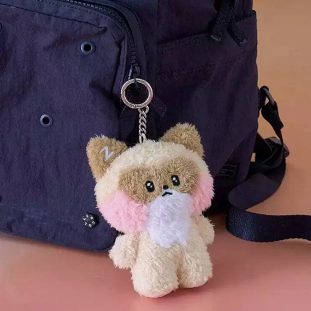 Plush kawaii keychain shaped like a bear with a pink bow tie attached to a dark blue bag.
