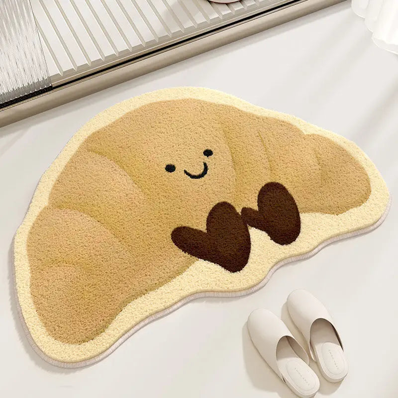 Cute cartoon-style croissant-shaped kawaii rug on a light surface with a pair of white slippers.