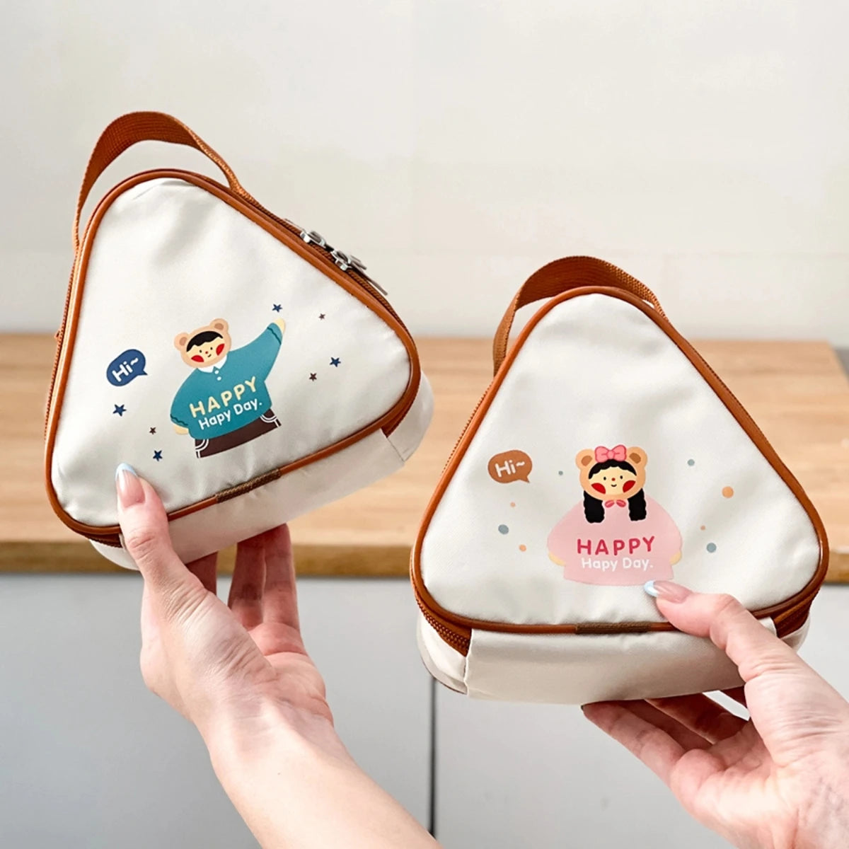 Two small pouches with kawaii cartoon characters and 'Happy Day' text held by hands against a neutral background.