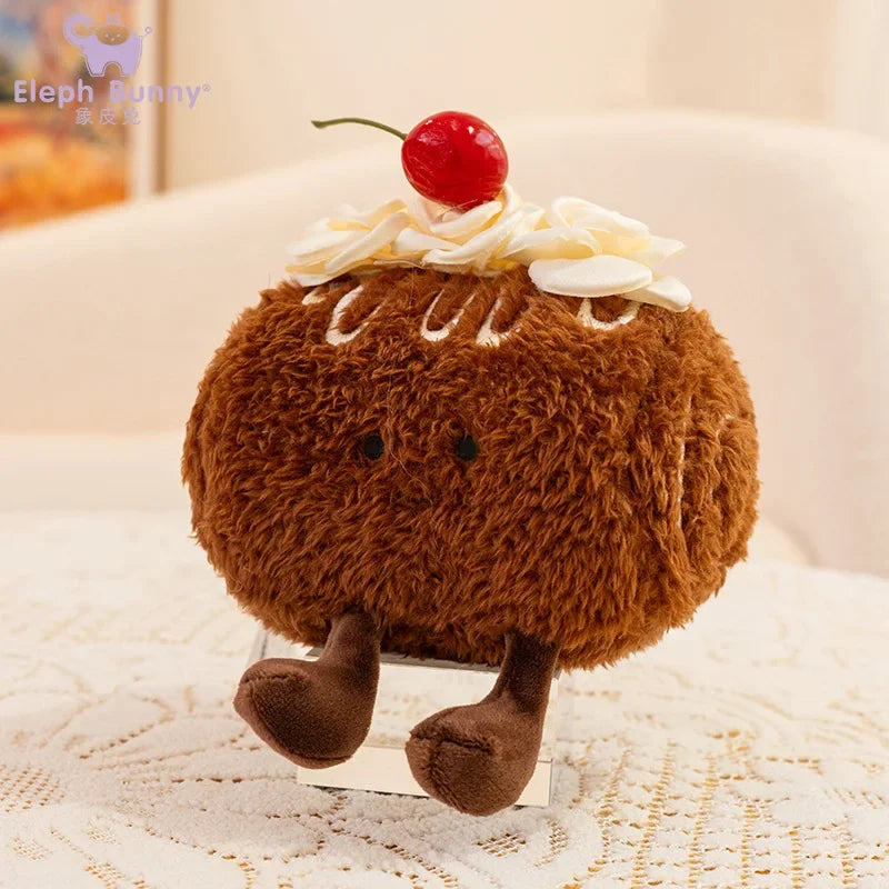 Kawaii plush toy resembling a cake with a cherry on top, sitting on a textured surface.