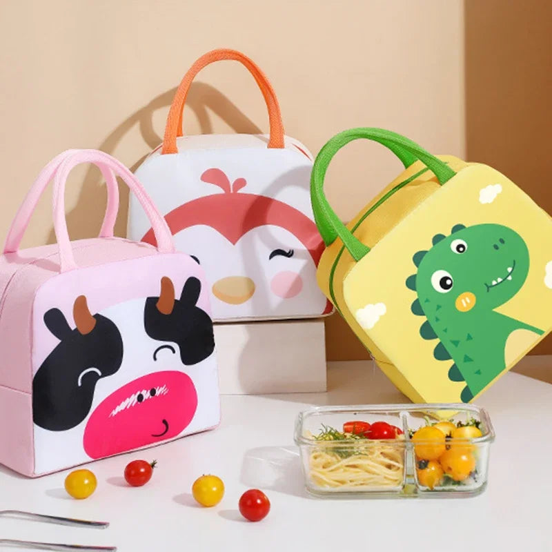 Three cartoon-themed kawaii lunch bags with a glass container of food on a white surface.