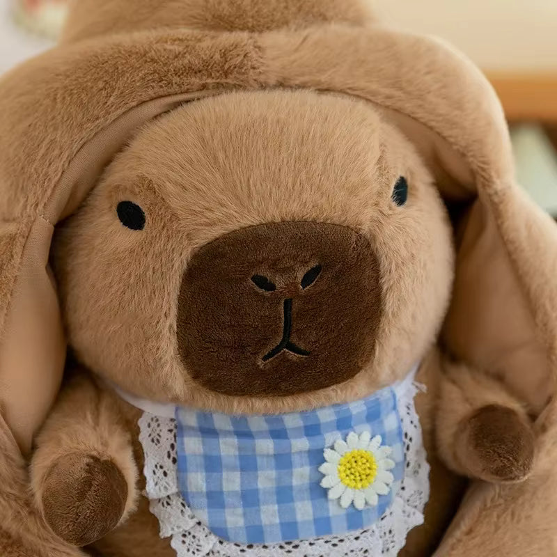 Brown kawaii plush toy with a checkered bib and flower decoration on a blurred background