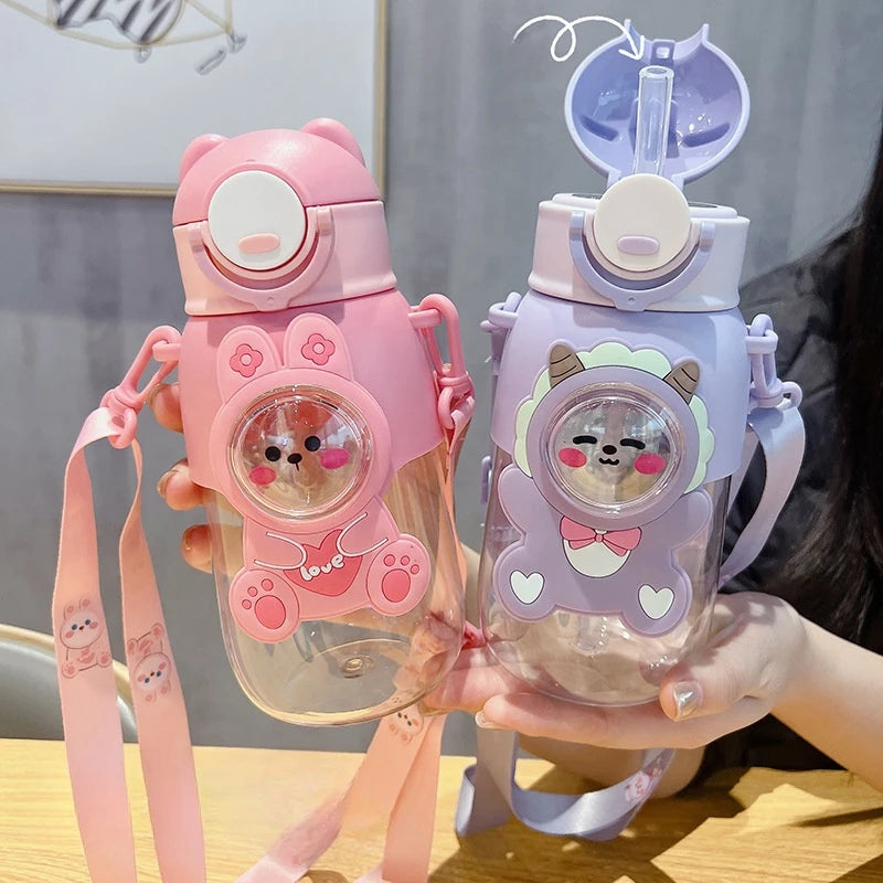 Two cartoon-themed kawaii water bottles held by a person, one pink and one purple, with cute animal faces on the lids.