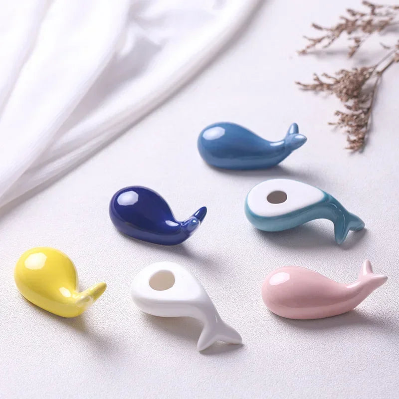 Colorful ceramic whale-shaped kawaii chopstick holders on a light background