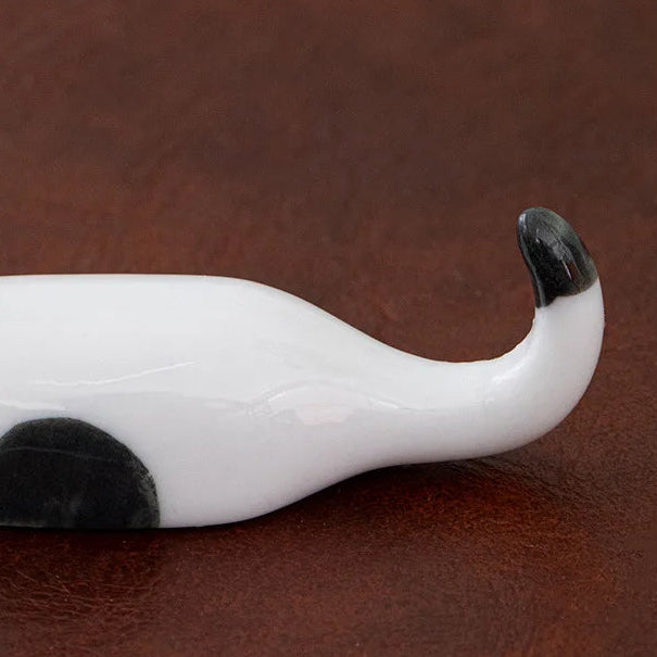 White ceramic kawaii chopstick holders with black accents on a brown leather background